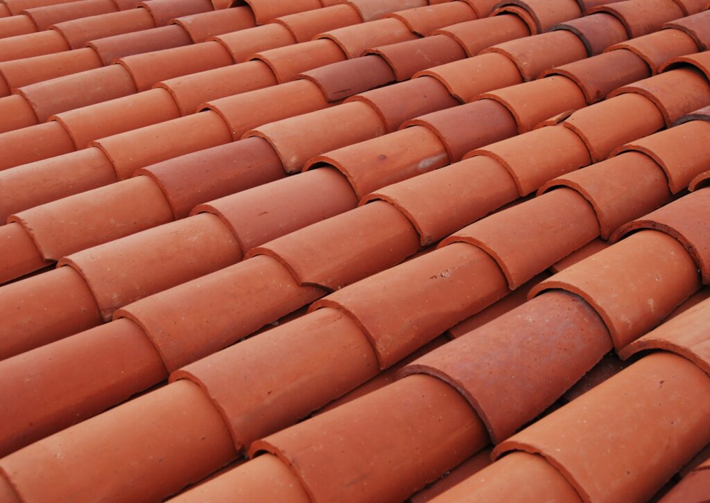 Close-up view of neatly arranged, weathered terracotta elements forming a repetitive, undulating pattern in warm with subtle color variations.