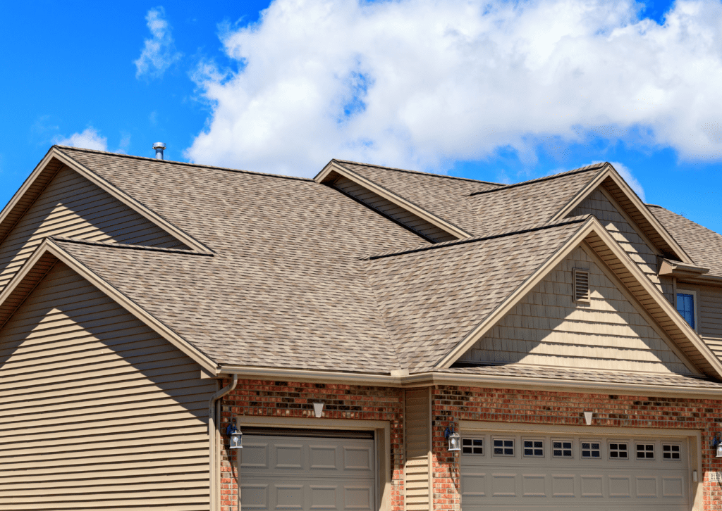 How to clean house roof: Maintain shingles on multi-gabled homes with tan siding, brick accents, and garage doors.