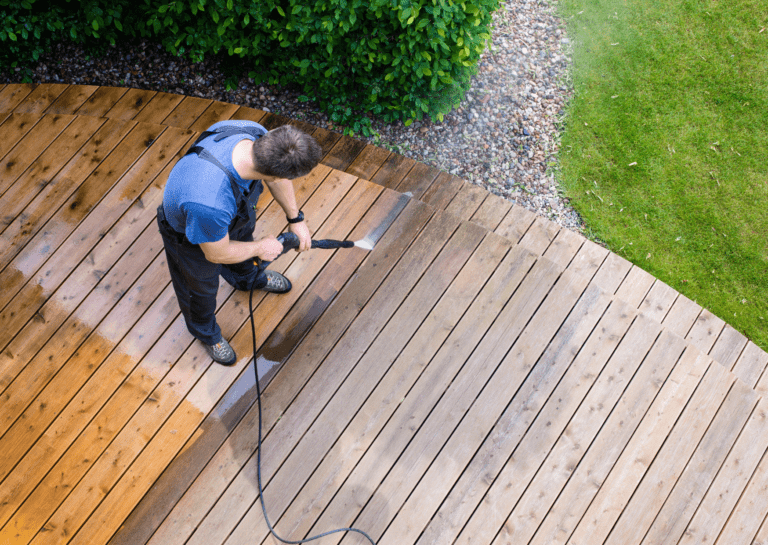 A worker pressure washing a wooden deck, demonstrating safe and effective soft washing for outdoor surfaces.