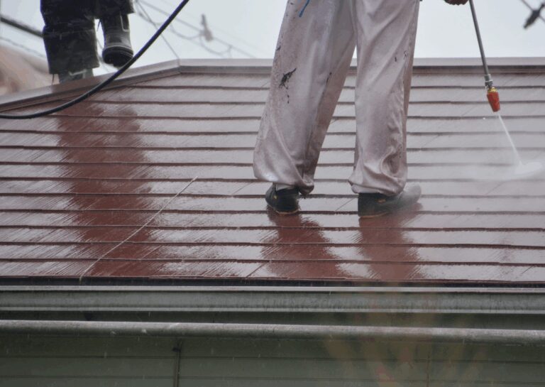 Person pressure washing a roof, an example of what is softwashing a roof for safe and effective surface cleaning.